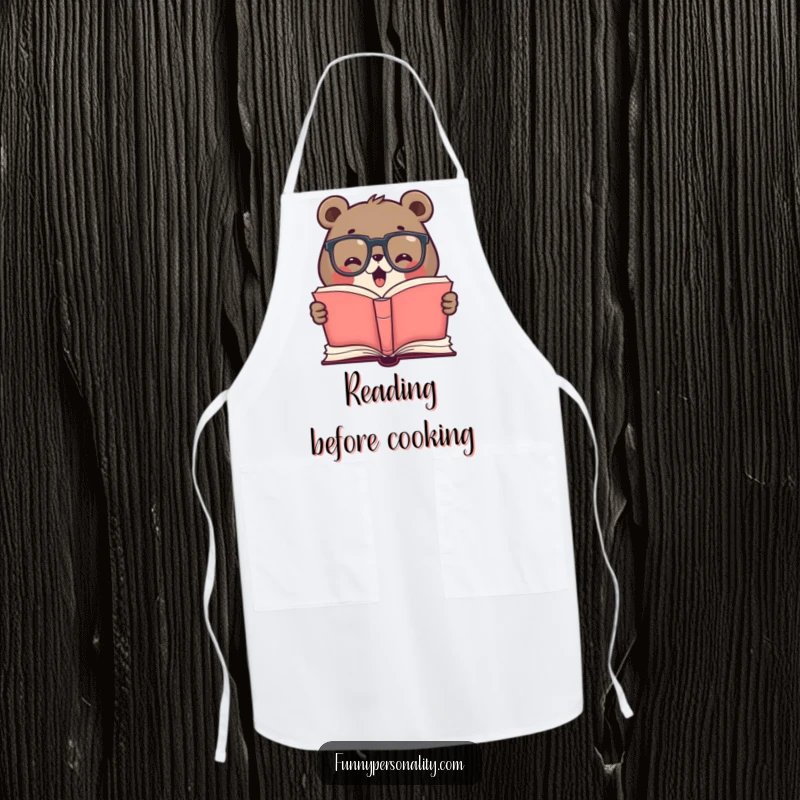 Funny apron with a cute bear wearing glasses, excitedly reading a giant open book, suitable for cooking and kitchen activities with a literary theme.
